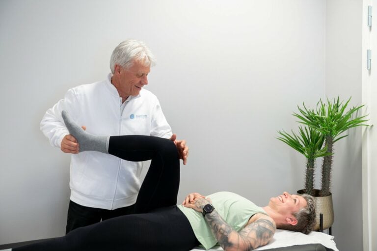 Idrettslege tester knefunksjon hos sin pasient og viser henne hvordan ulike begevelsesbaner påvirker hennes smerter i kne og øvre rygg